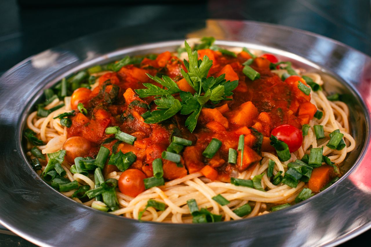 Close-up of a vibrant vegetable spaghetti dish with fresh tomato sauce and herbs.
